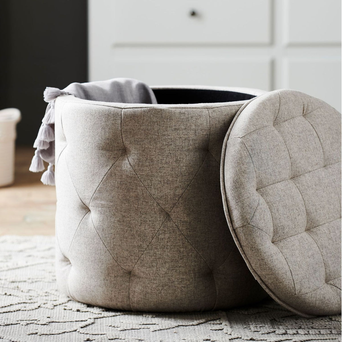 Beige tufted ottoman with a lid on a textured rug