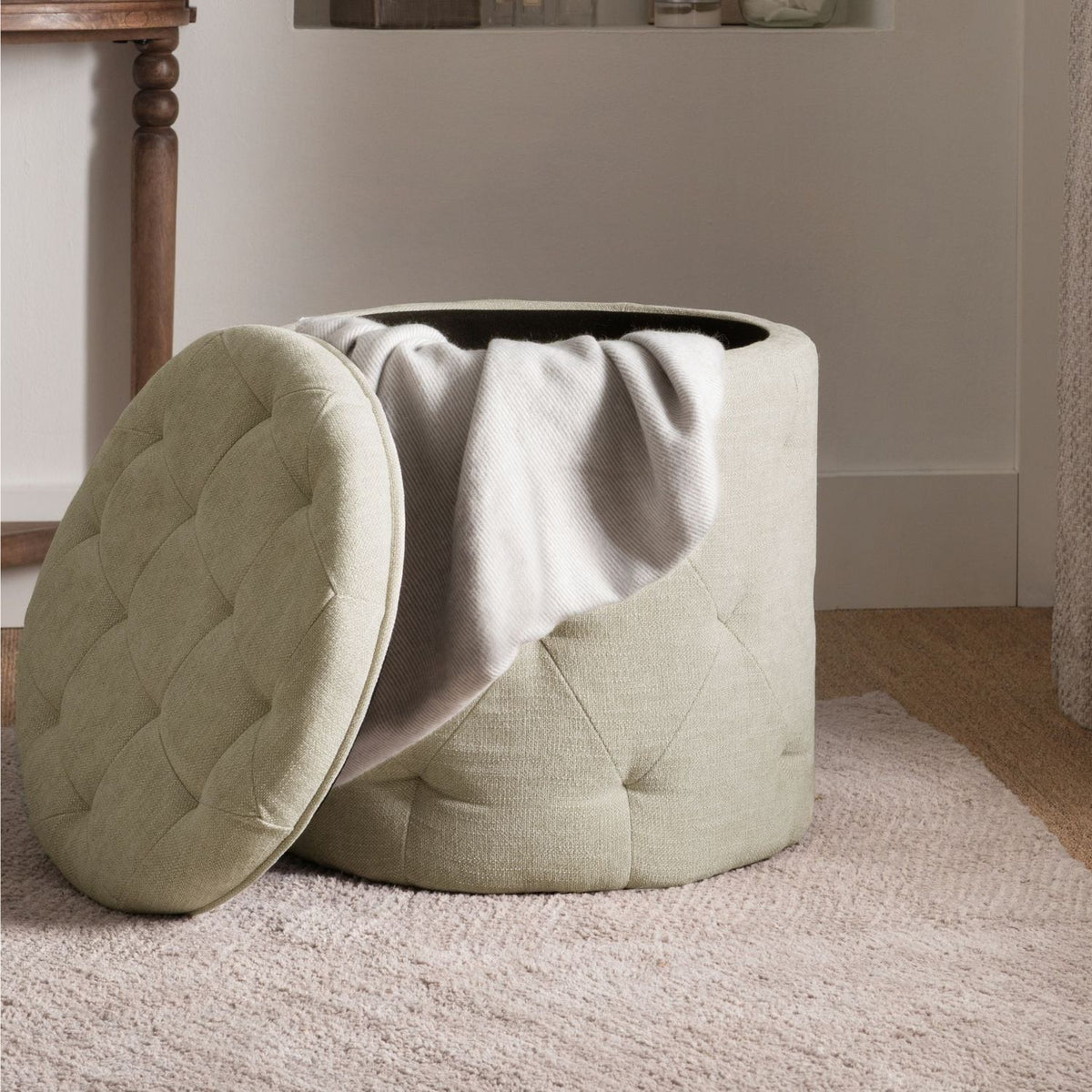 Light green ottoman with quilted lid on a carpeted floor