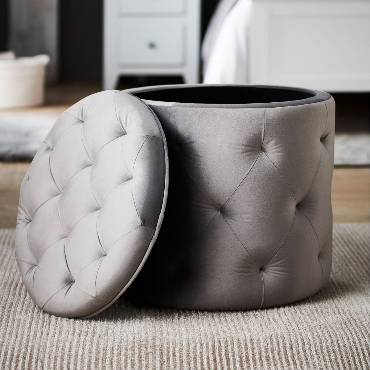 Gray tufted storage ottoman on a carpeted floor