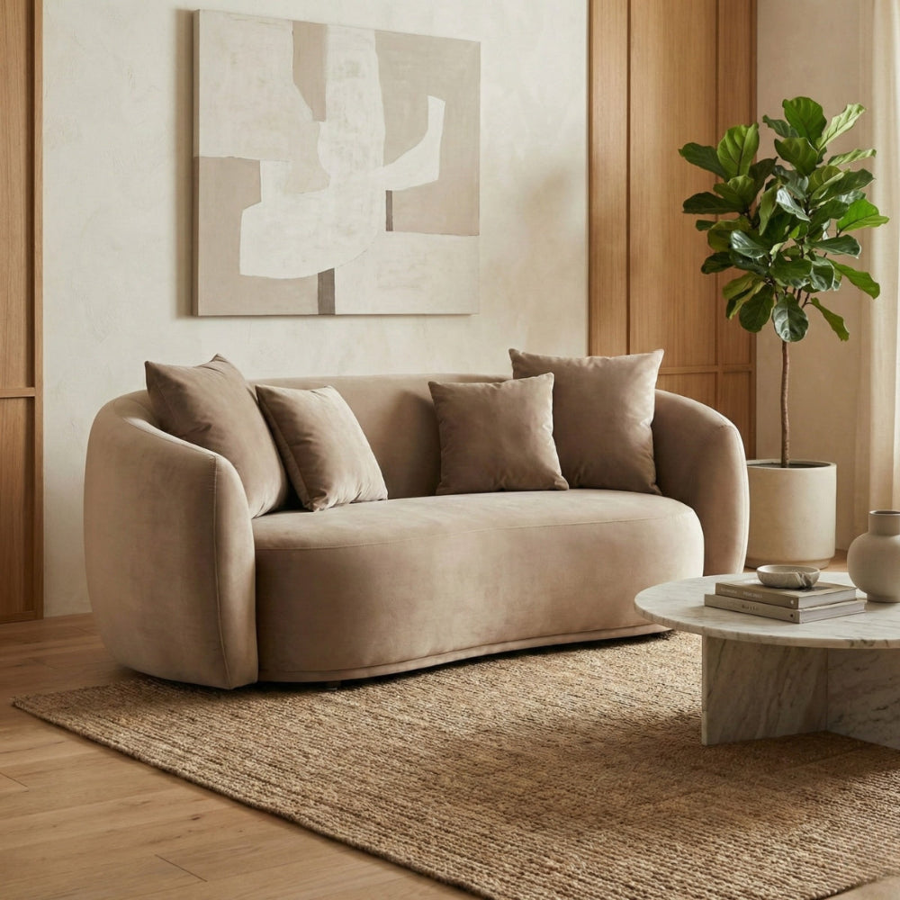 Beige sofa in a living room with a coffee table, plant, and abstract art on the wall.