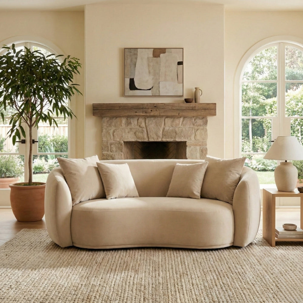 Beige sofa in a living room with a fireplace and large windows.