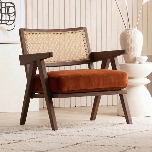 Wooden armchair with wicker backrest and orange cushion in a room setting.