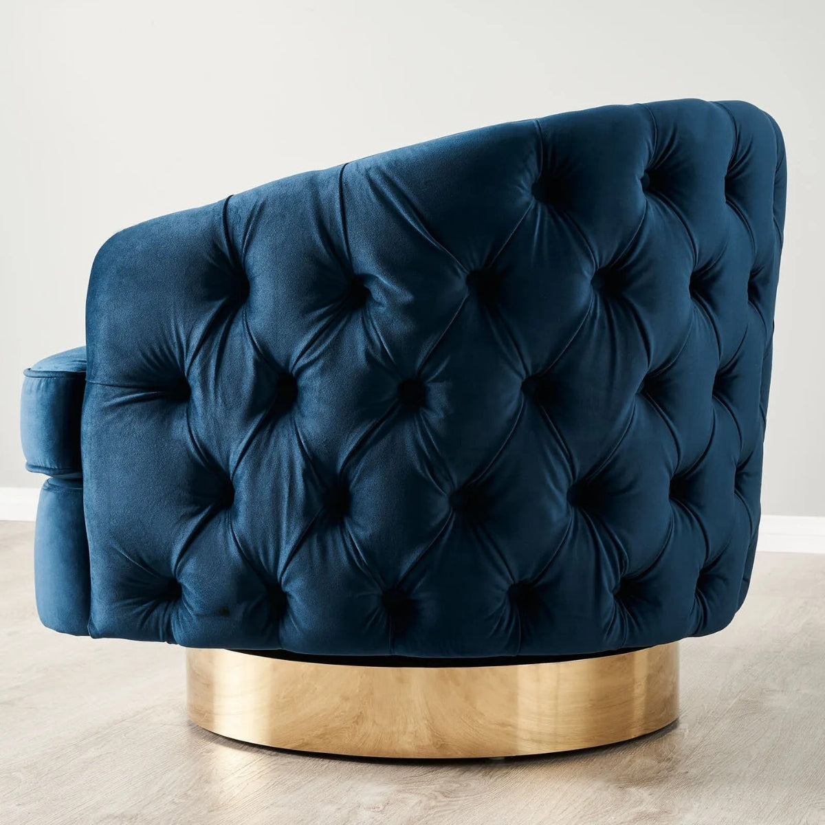 Blue tufted chair with a gold base on a light background
