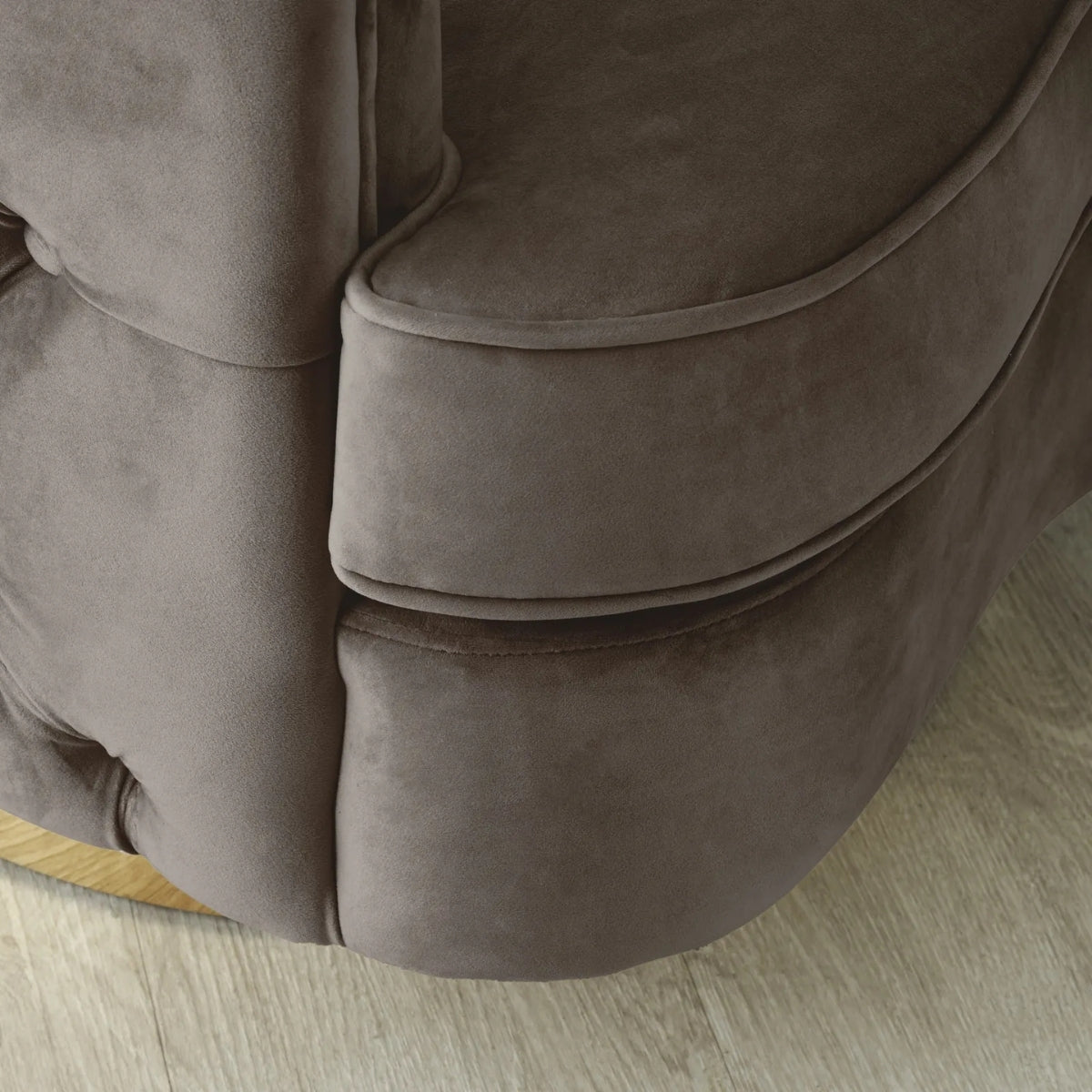 Close-up of a brown textured surface, possibly a sofa or cushion, on a light wooden floor.