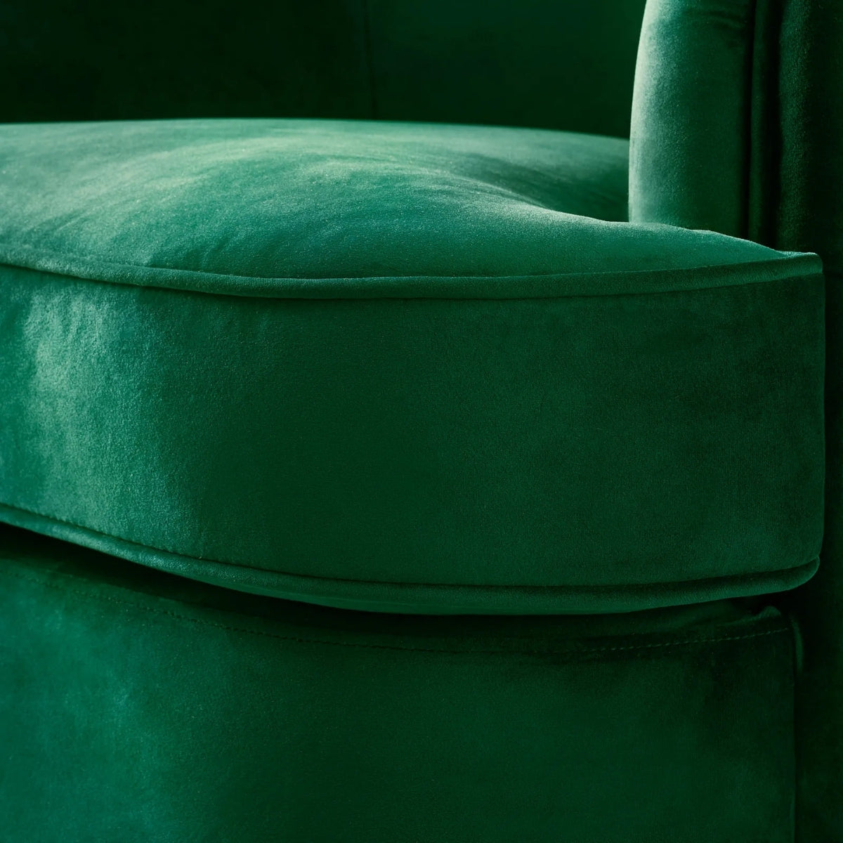 Close-up of a green velvet chair with a dark background
