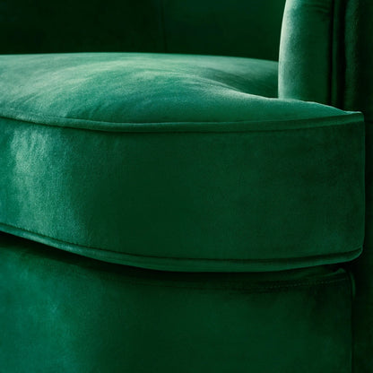 Close-up of a green velvet chair with a dark background