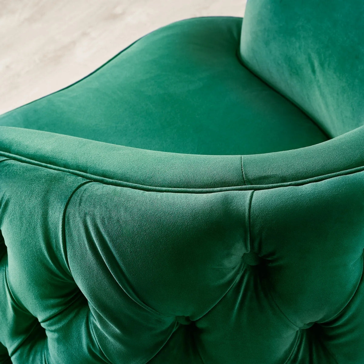 Close-up of a green velvet chair with tufted details