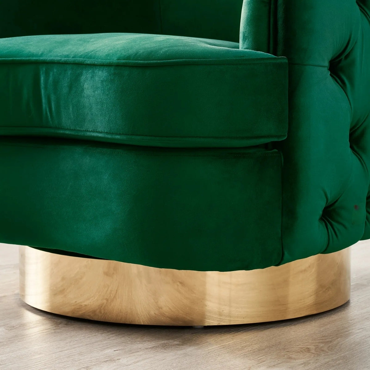 Green velvet armchair with a gold base on a wooden floor