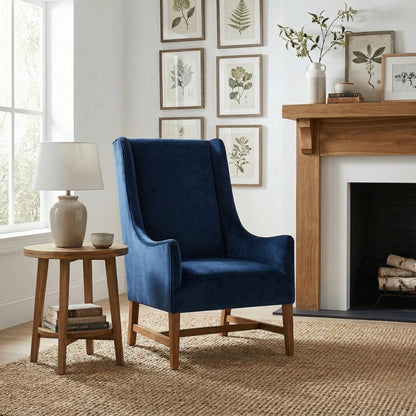 Blue armchair in a living room with a wooden side table, lamp, and fireplace.