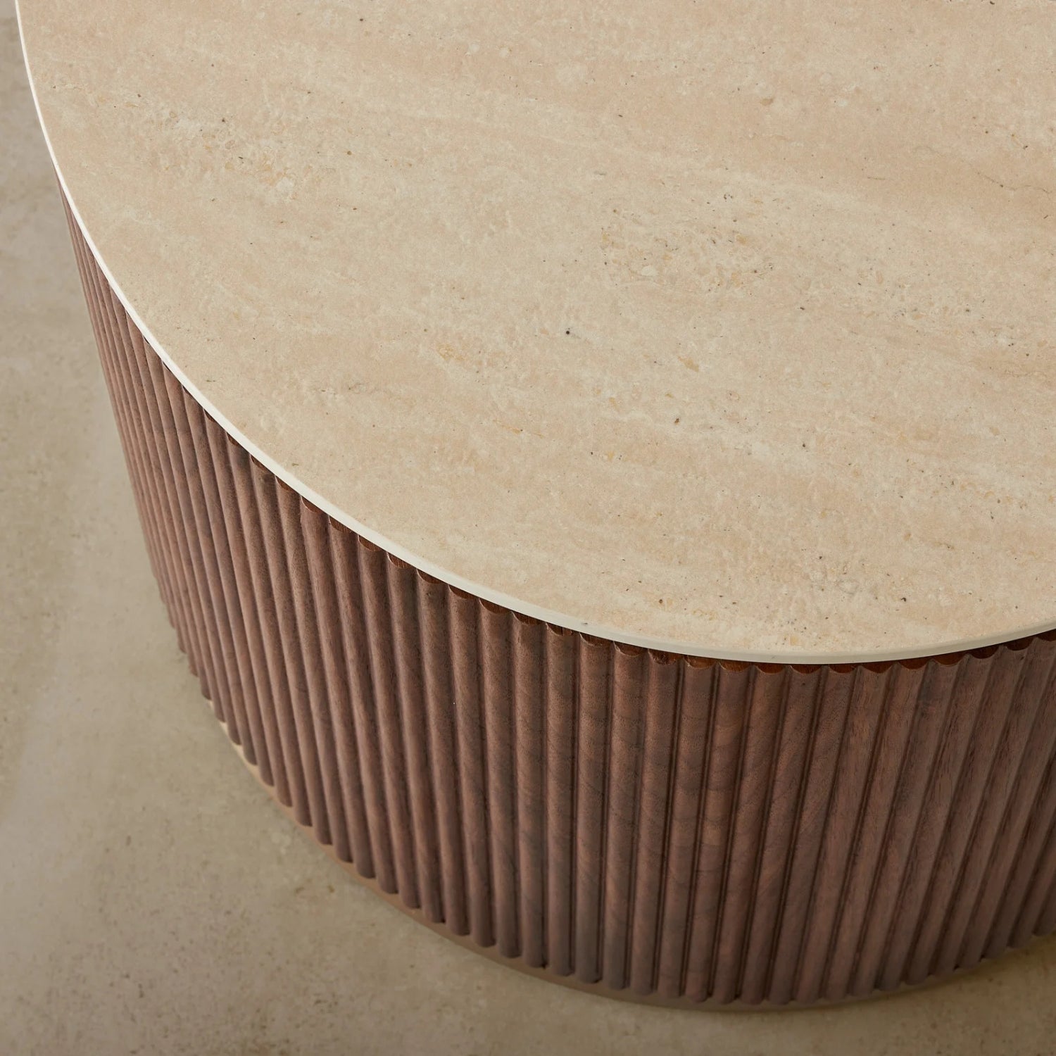 Round table with a textured surface and ribbed base on a neutral background