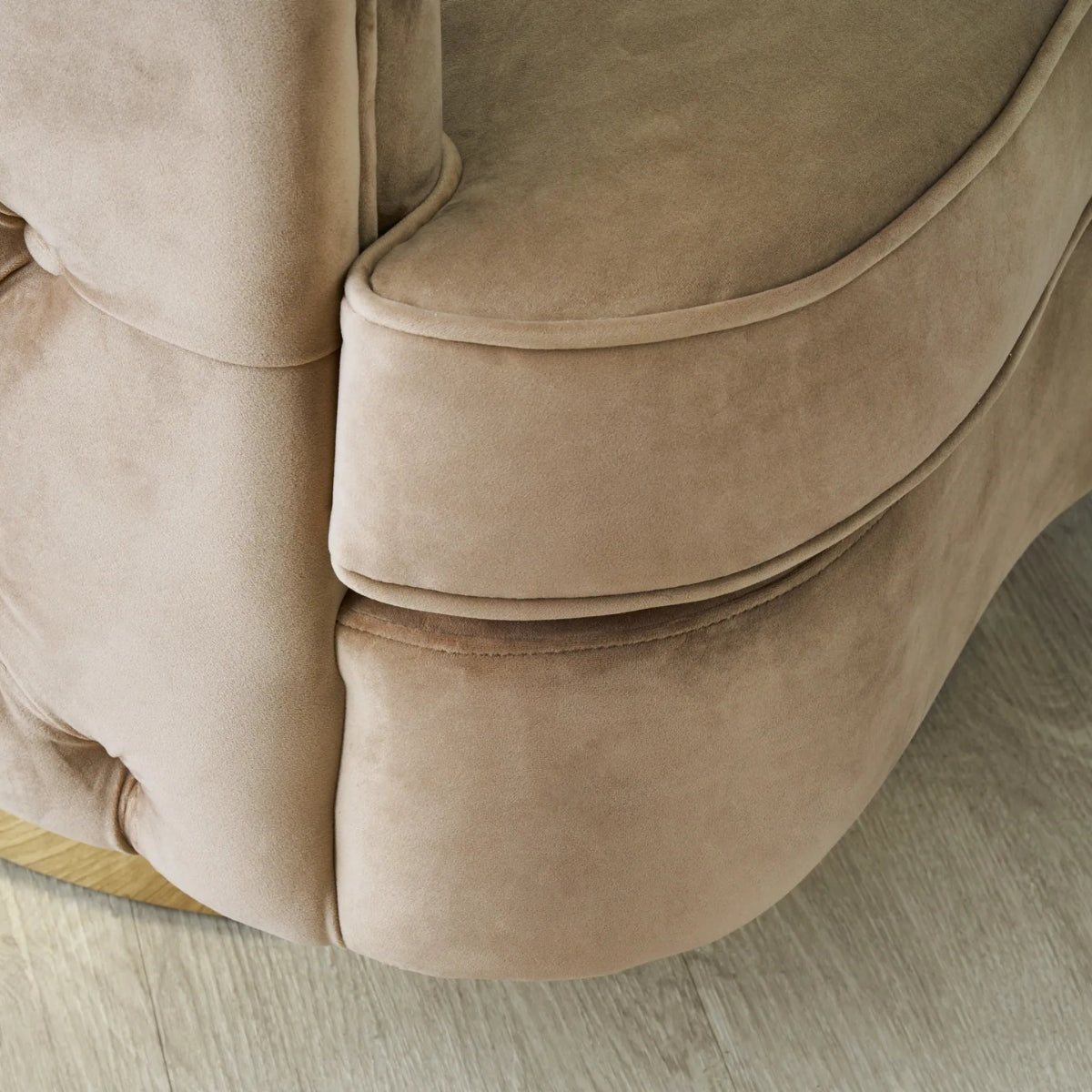Close-up of a beige sofa with a soft texture on a light wooden floor.