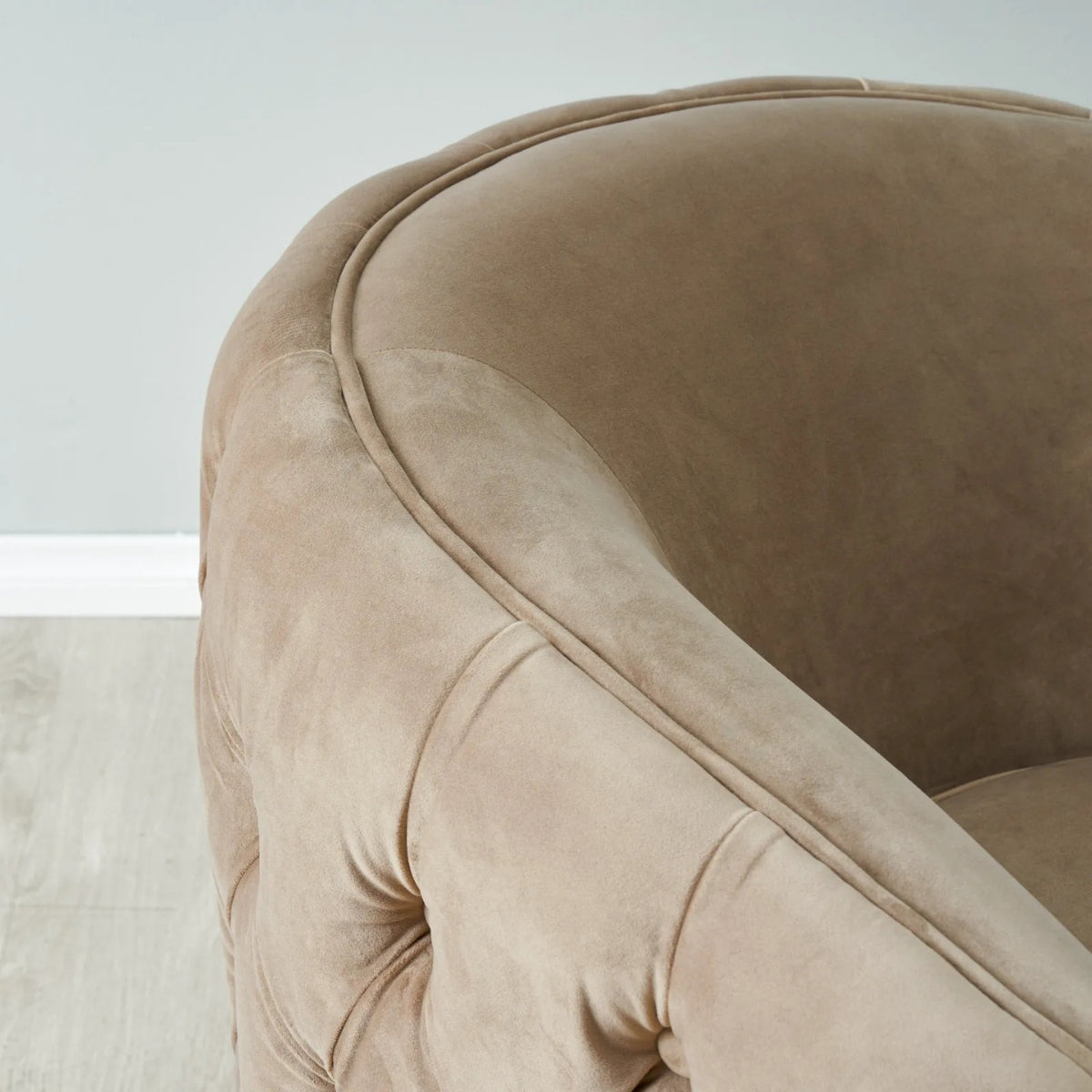 Close-up of a beige velvet armchair with a neutral background