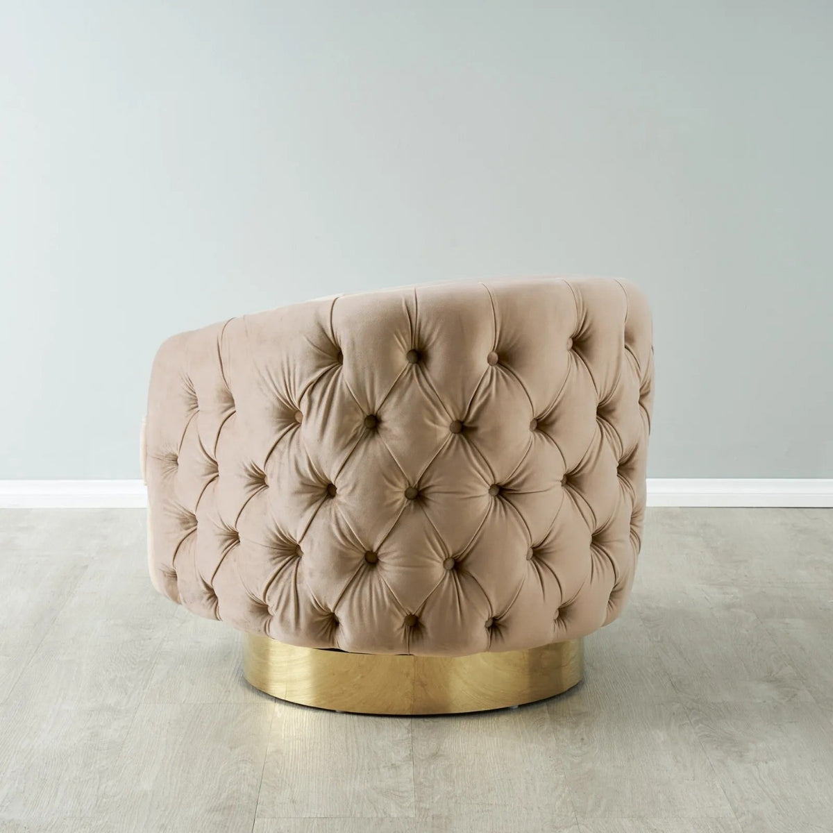 Pink tufted chair with gold base on a light gray floor and white wall background