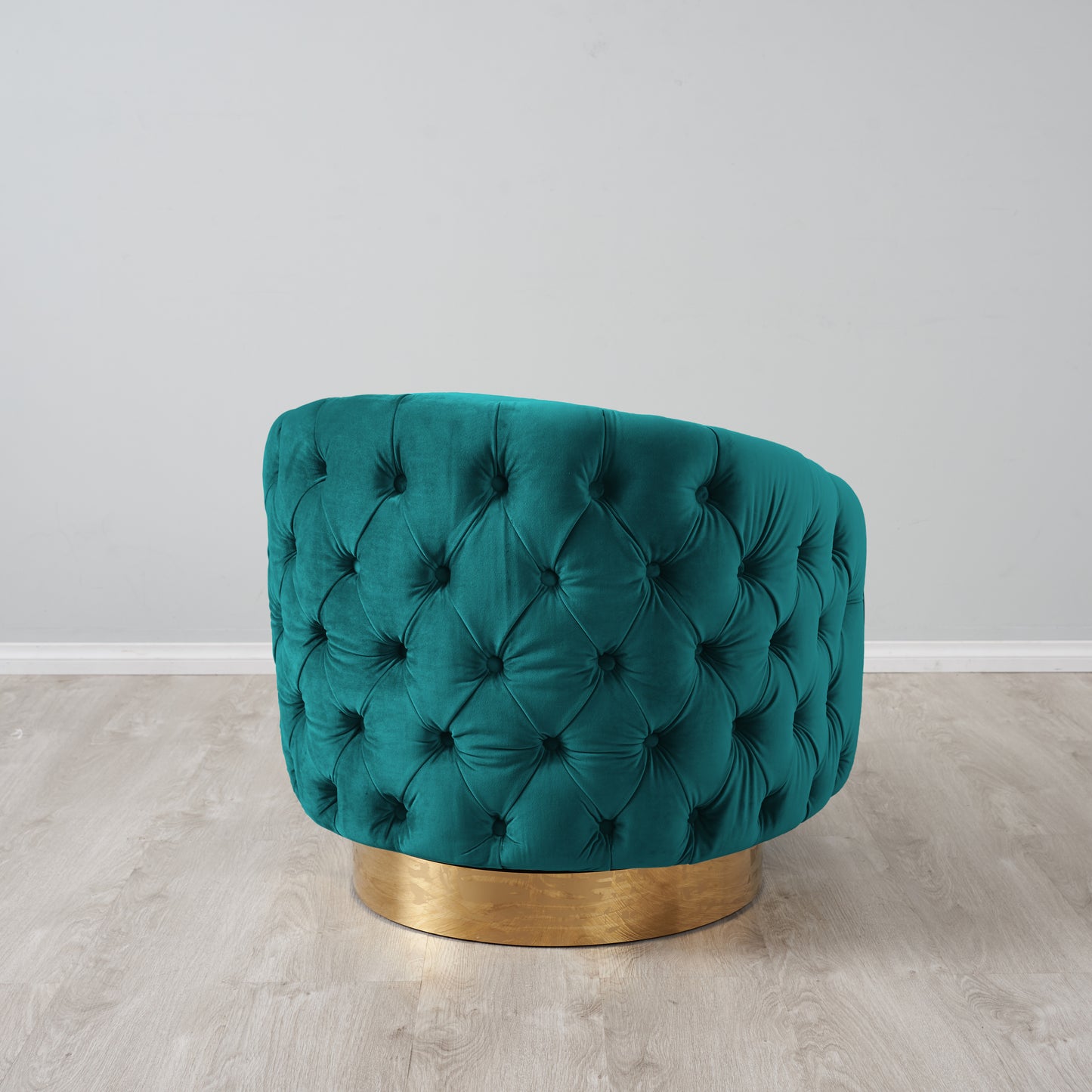 Teal tufted chair with gold base on a light wooden floor against a gray wall