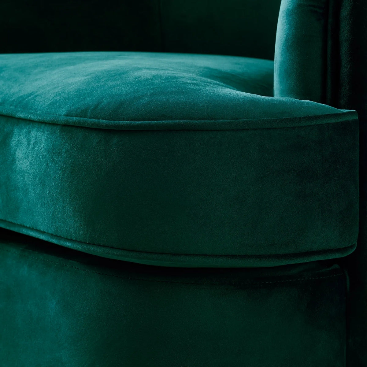 Close-up of a teal velvet chair with a dark background