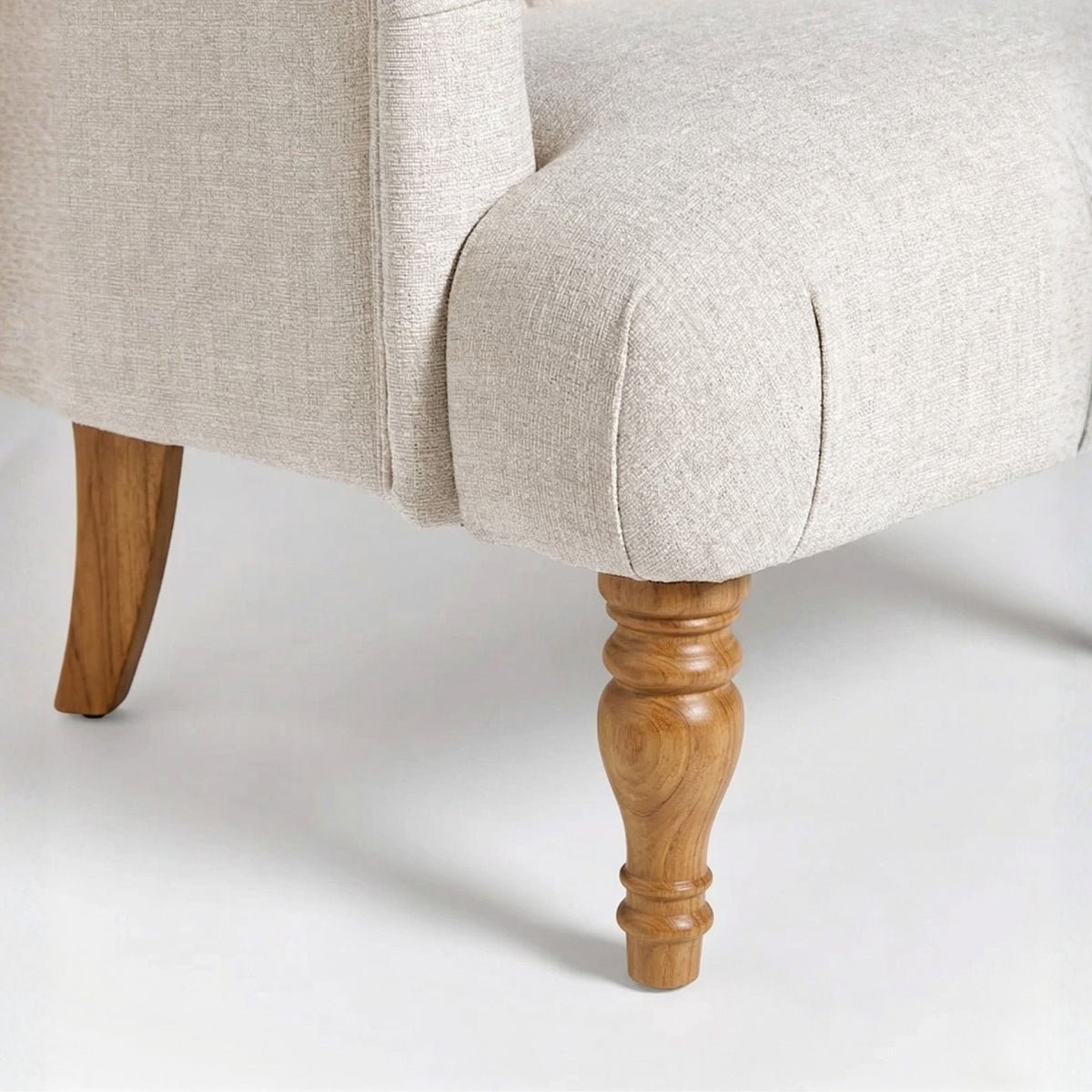 Close-up of a beige upholstered chair with wooden legs on a white background