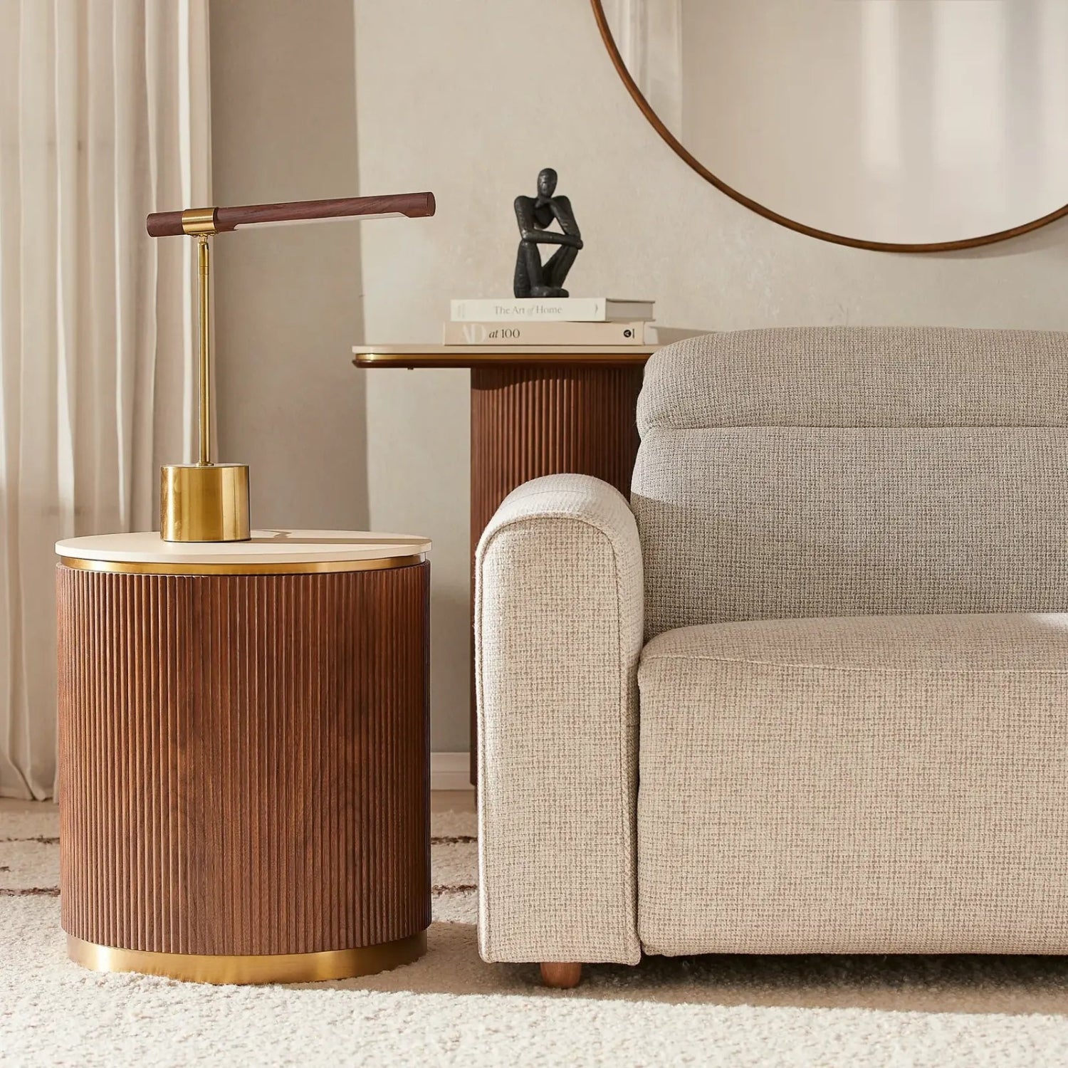 Wooden side table with gold accents next to a beige sofa in a living room setting.