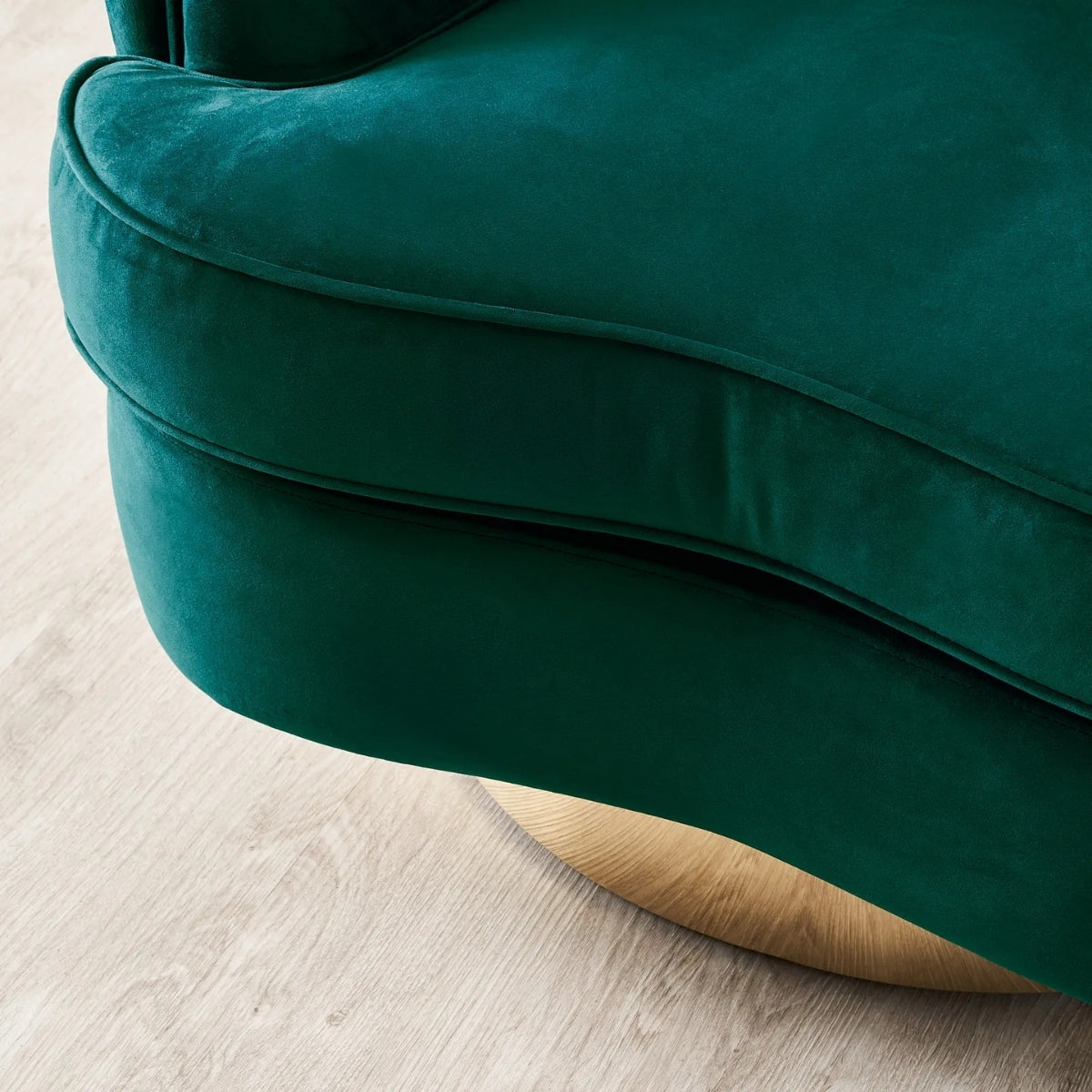 Close-up of a green velvet armchair on a light wooden floor