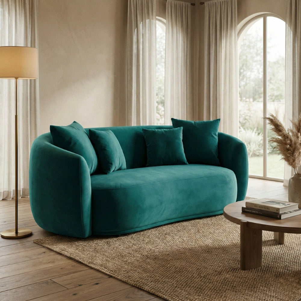 Teal sofa in a living room with wooden coffee table and lamp.