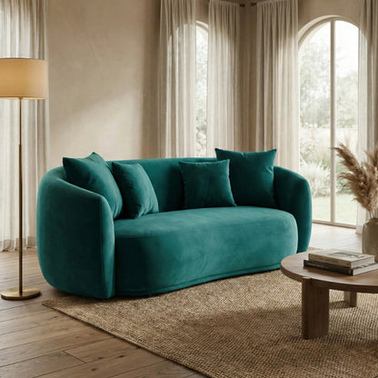 Teal sofa in a living room with wooden coffee table and lamp.