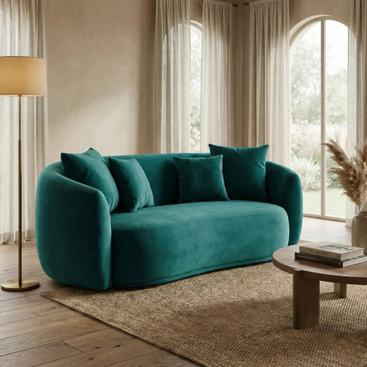 Teal sofa in a living room with wooden coffee table and lamp.