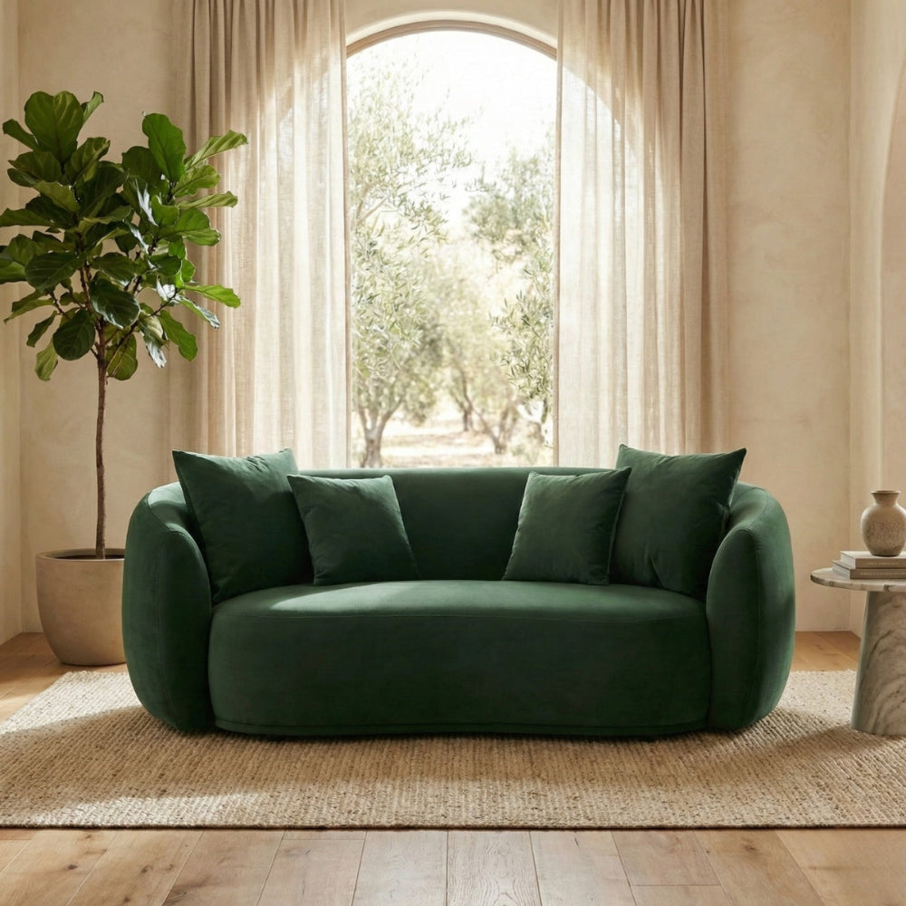 Green sofa in a living room with a plant and a window in the background