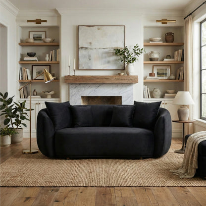 Modern living room with a black sofa, fireplace, and bookshelves.